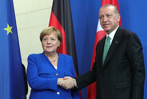 ＥＵ主要国はトルコへの軍事機器の輸出を停止するなど、制裁を強めている。写真は握手をするメルケル独首相とエルドアン大統領 (C)Bloomberg/Getty Images