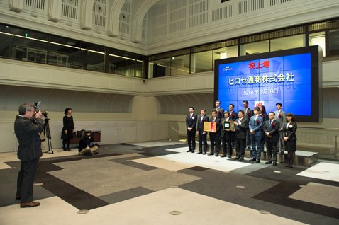 電光掲示板の前で、細合俊一社長をはじめ関係者が記念撮影